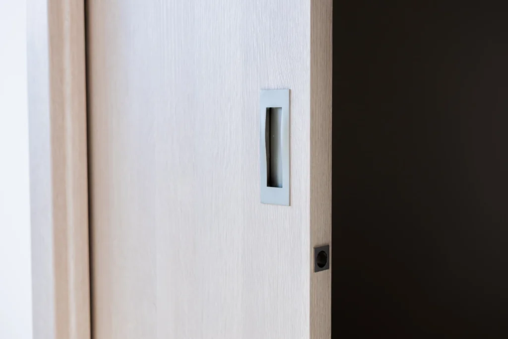 Detail na světlé dřevěné posuvné dveře vedoucí do šatny z ložnice v rodinném domě v Kostelci nad Labem.
