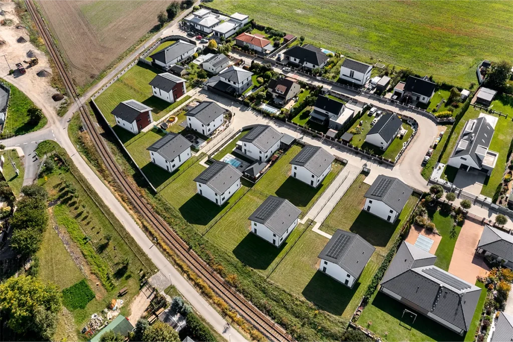 Letecký pohled na rezidenční lokalitu s moderními rodinnými domy, zahradami a fotovoltaickými panely v Kostelci nad Labem.
